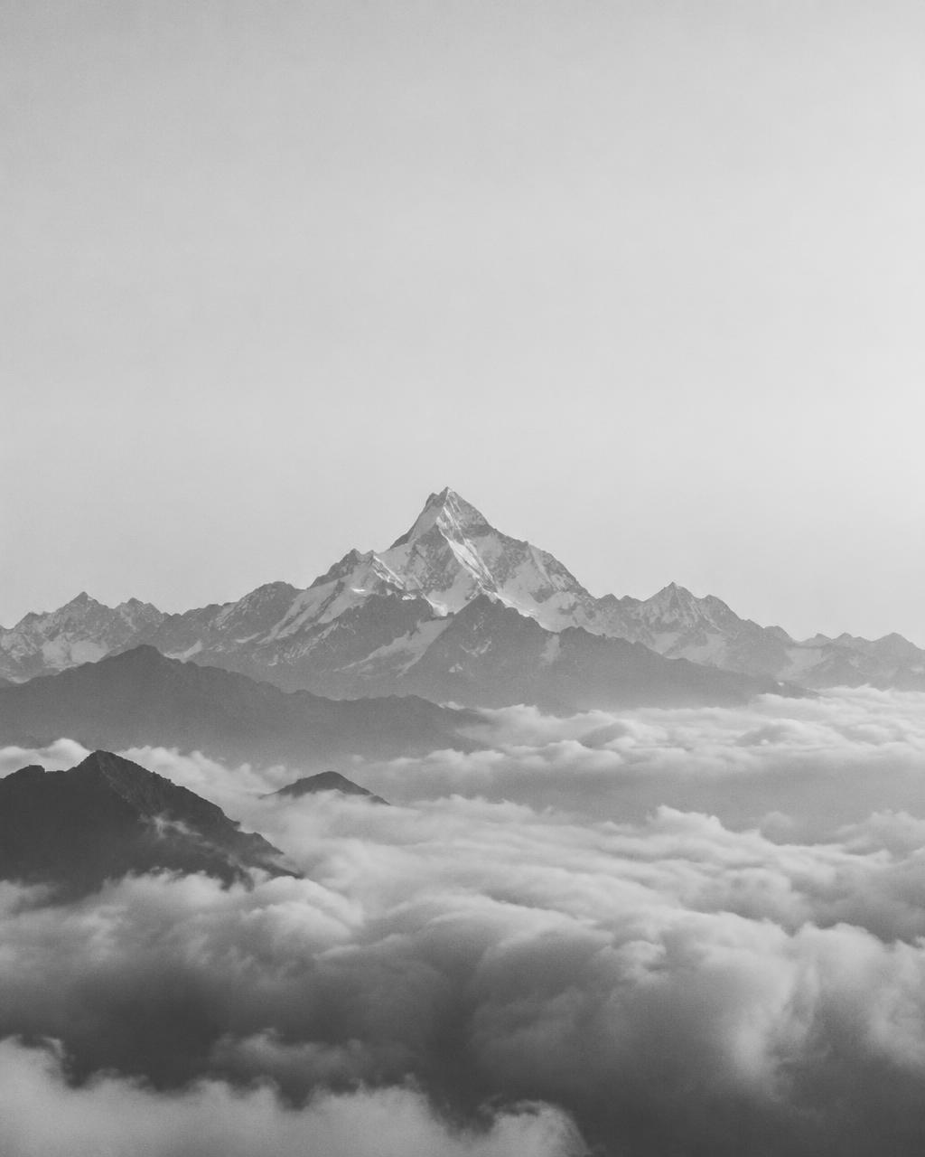 A high mountain peak seen from a distance, above a sea of clouds